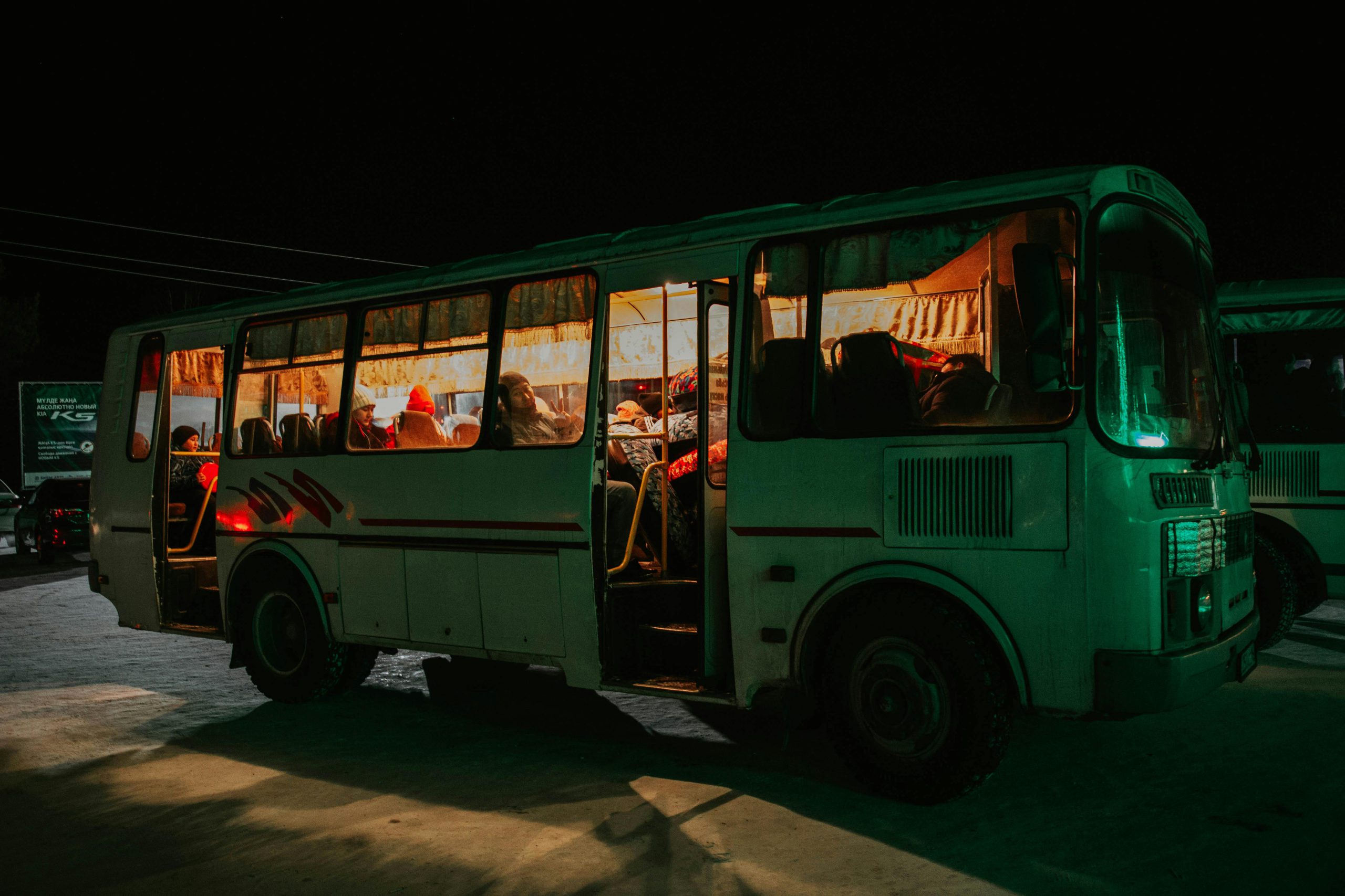 Stary autobus z ludźmi w środku w nocy bo to przewóz osób